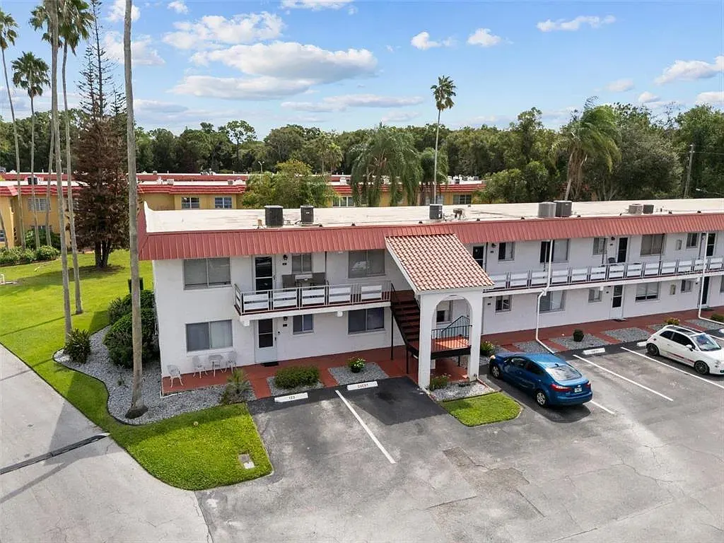 Two-story Orchid Springs building with red roof, palms and green lawn
