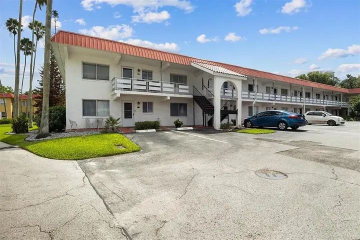 Long two-story garden building with parked cars