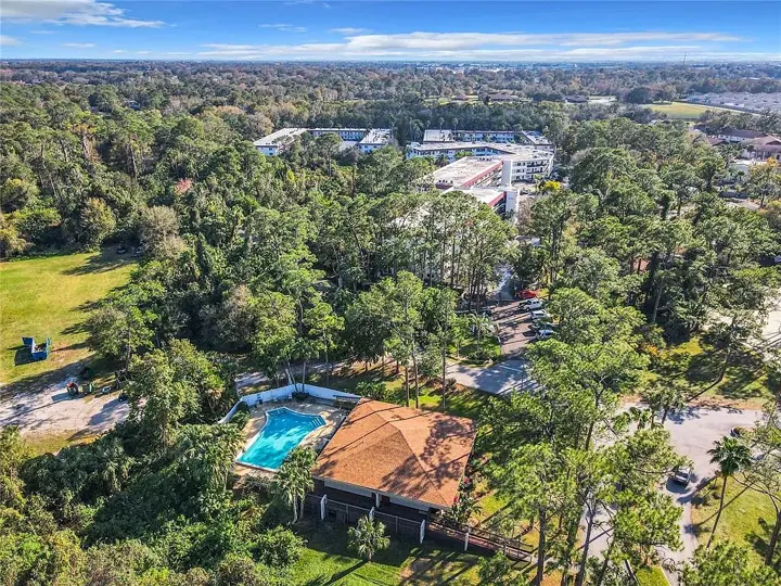 Pool and clubhouse surrounded by tall trees